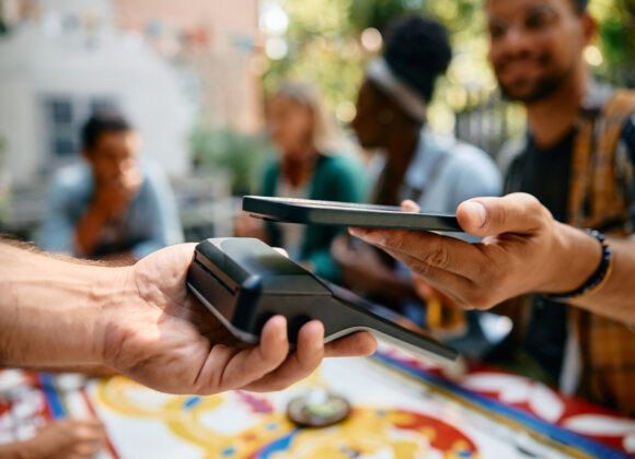 तांत्रिक क्रांतीची दोन रूपं - भारतातला UPI आणि अमेरिकेतला AI Close up of man using smart phone while paying to a waiter in a cafe.