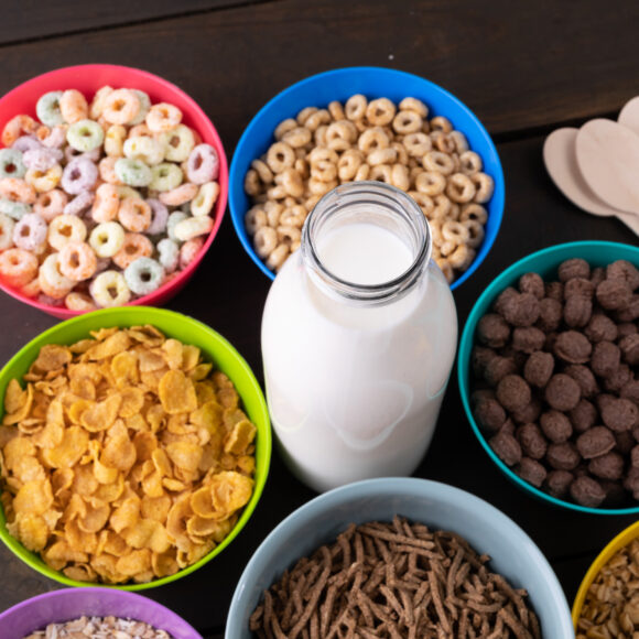 High angle view of various breakfast cereals in bowls arranged with milk bottle on table. unaltered, breakfast, variation, healthy food, snack and food concept.